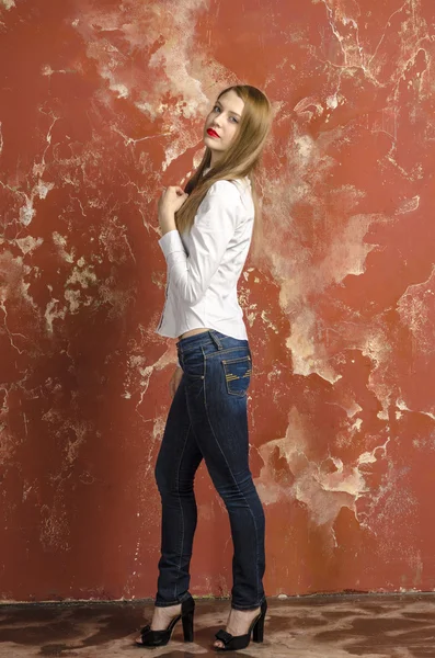 Young beautiful long-haired brown-haired woman in unbuttoned white shirt and jeans — Stock Photo, Image