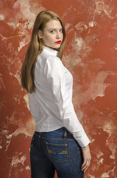 Unga vackra långhåriga brunhårig kvinna i uppknäppt vit skjorta och jeans — Stockfoto