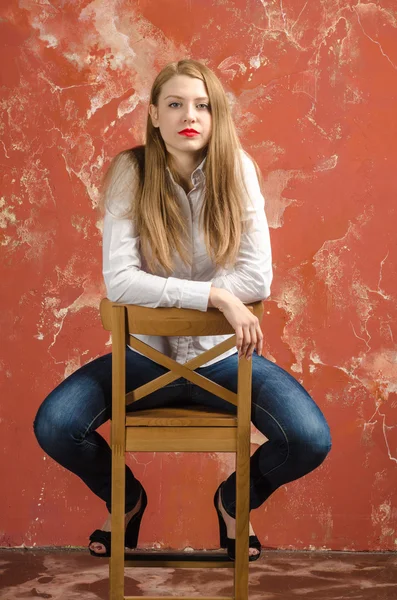 Молода красива довгошерста коричнево-волохата жінка в білій сорочці і джинсах — стокове фото