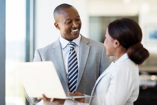 Workers with laptop inside car showroom — Stock Photo, Image