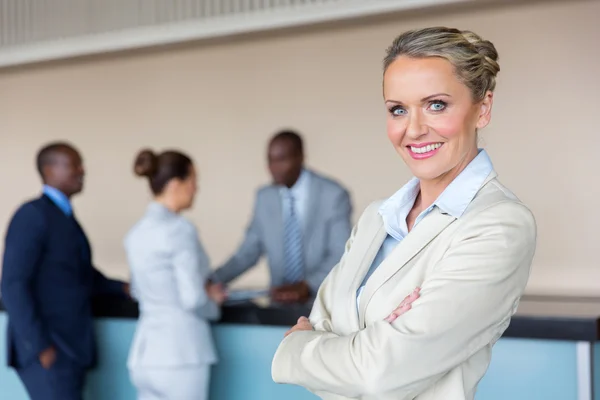 Mujer de negocios de pie en la recepción del hotel con sus colegas Imagen de archivo