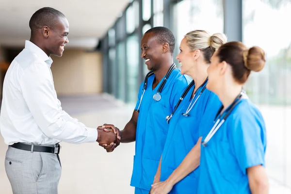 Representante médico aperto de mão com médicos no hospital — Fotografia de Stock