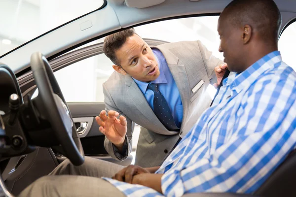 Salesman showing car interior to customer — Stock Photo, Image