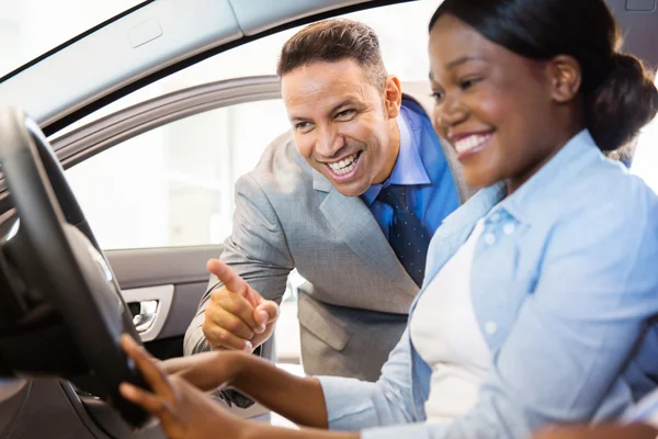 Försäljaren visar bil till kvinnlig kund Stockbild
