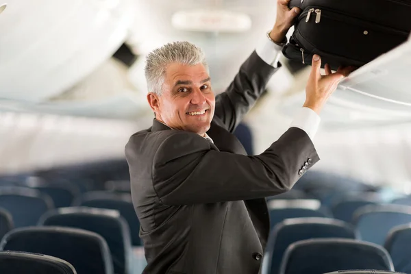 Business traveler putting luggage away — Stock Photo, Image