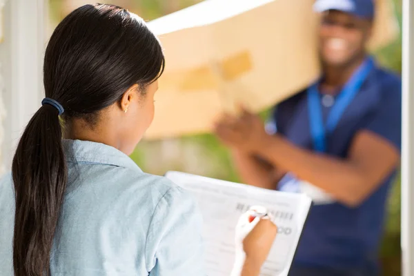 Vrouw ondertekening ontvangende papier — Stockfoto