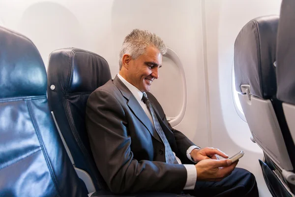 Businessman using cell on airplane — Stock Photo, Image