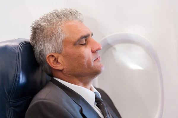 Сонный бизнесмен в самолете — стоковое фото