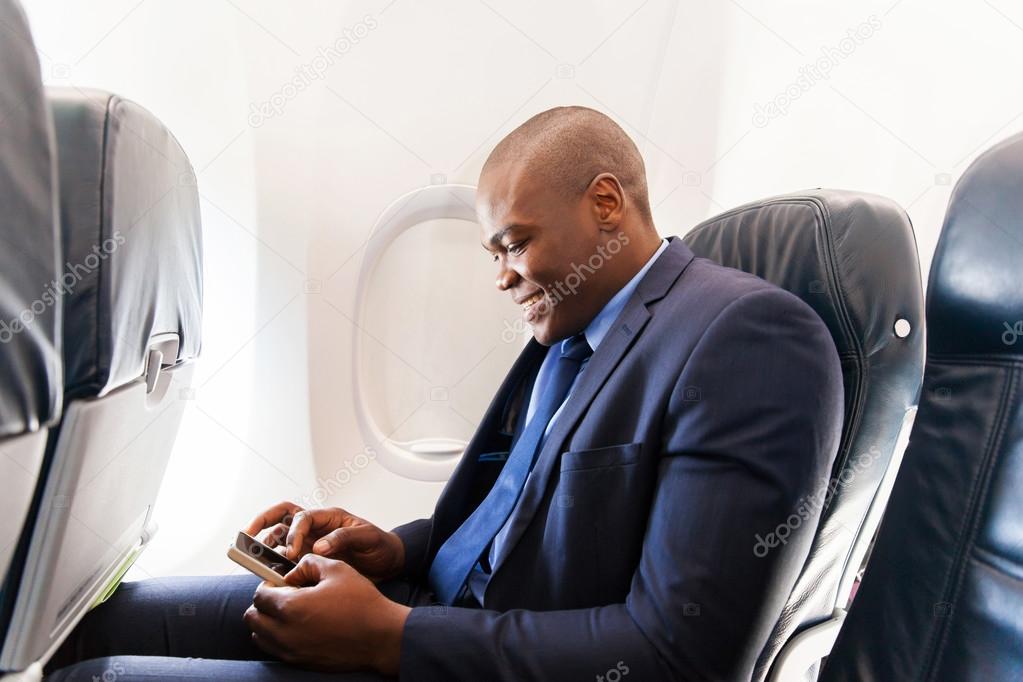 African airplane passenger using smartphone