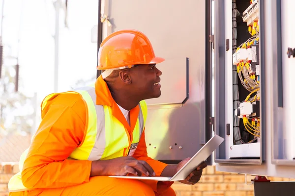 Afrikanischer Elektriker überprüft Status computergesteuerter Maschinen — Stockfoto