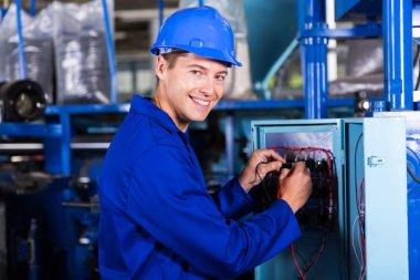 endüstriyel makine üzerinde çalışan elektrikçi