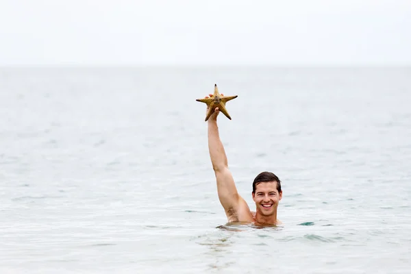 Hombre sosteniendo estrellas de mar —  Fotos de Stock