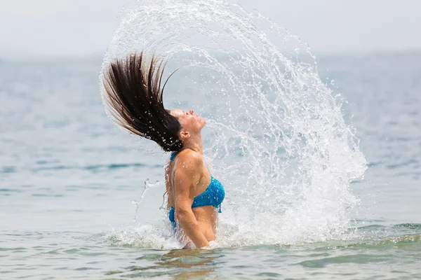 Frau im Wasser wedelt mit Haaren — Stockfoto