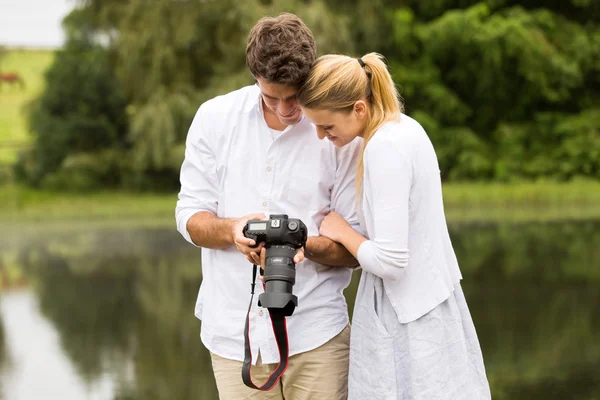 Jeune couple regardant des photos sur la caméra — Photo