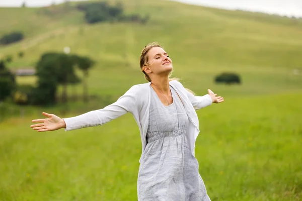 Young woman with arms open on grassland — Stock Photo, Image