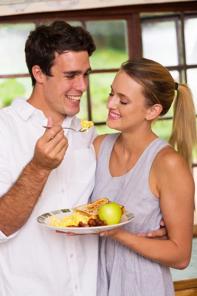 Junger Mann füttert seine Freundin beim Frühstück — Stockfoto