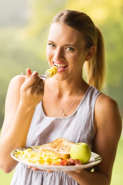 Mujer joven comiendo huevos revueltos — Foto de Stock