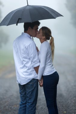 boyfriend and girlfriend kissing in the rain