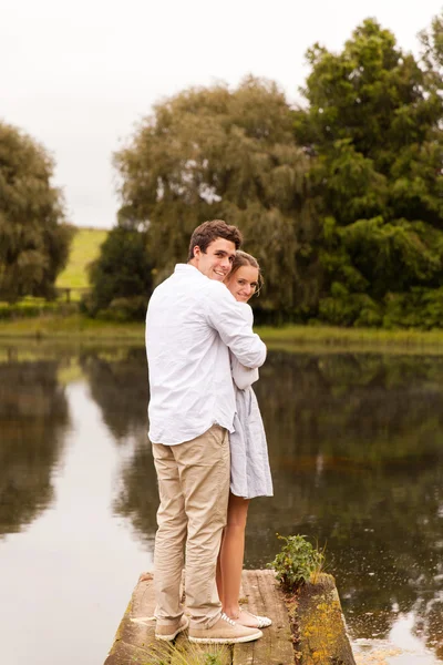 Joven pareja de pie en el muelle del río —  Fotos de Stock