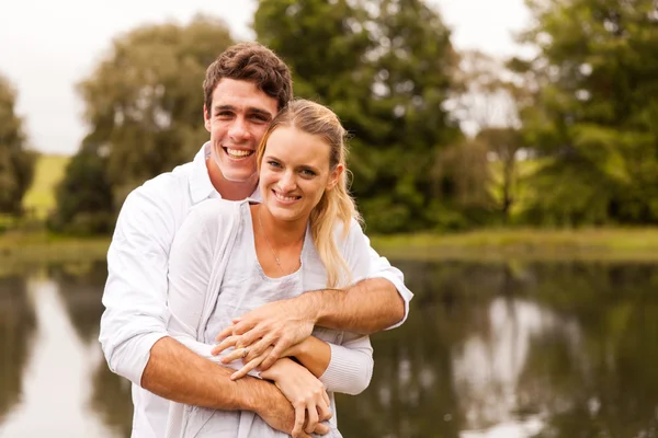 Pareja joven abrazándose junto al lago — Foto de Stock