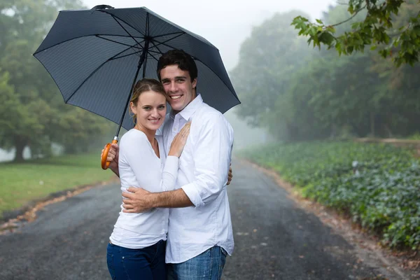 Νεαρό ζευγάρι κάτω από μια ομπρέλα στην ομίχλη — Φωτογραφία Αρχείου