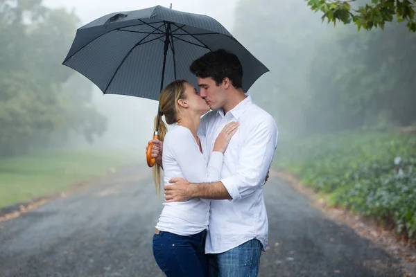 Casal beijando sob um guarda-chuva — Fotografia de Stock