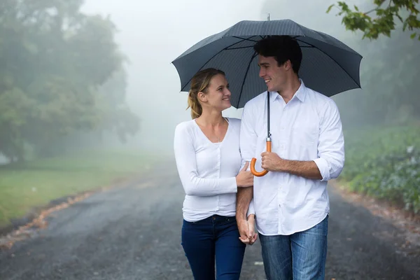 Pareja caminando bajo paraguas en el bosque — Foto de Stock