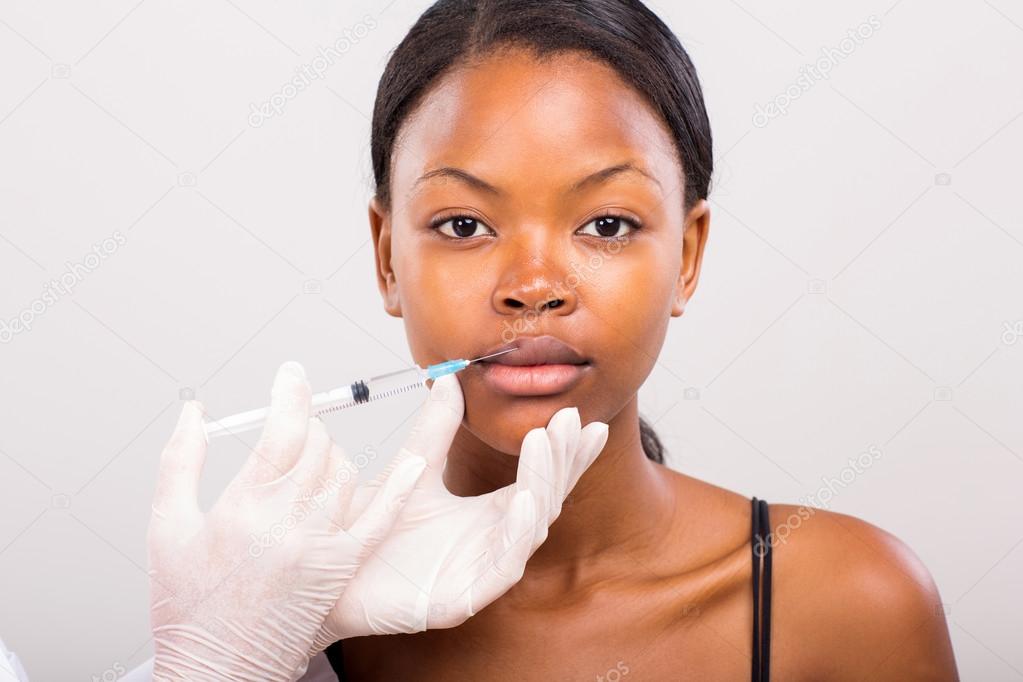 Woman receiving cosmetic injection in lips