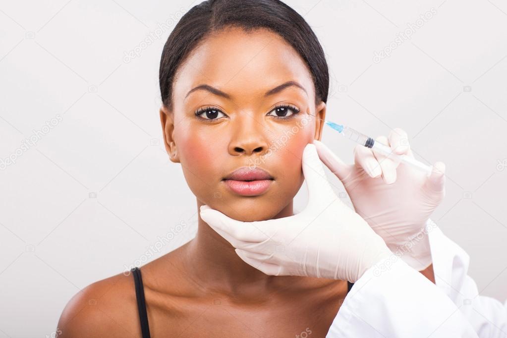 Cosmetic surgeon injecting woman face