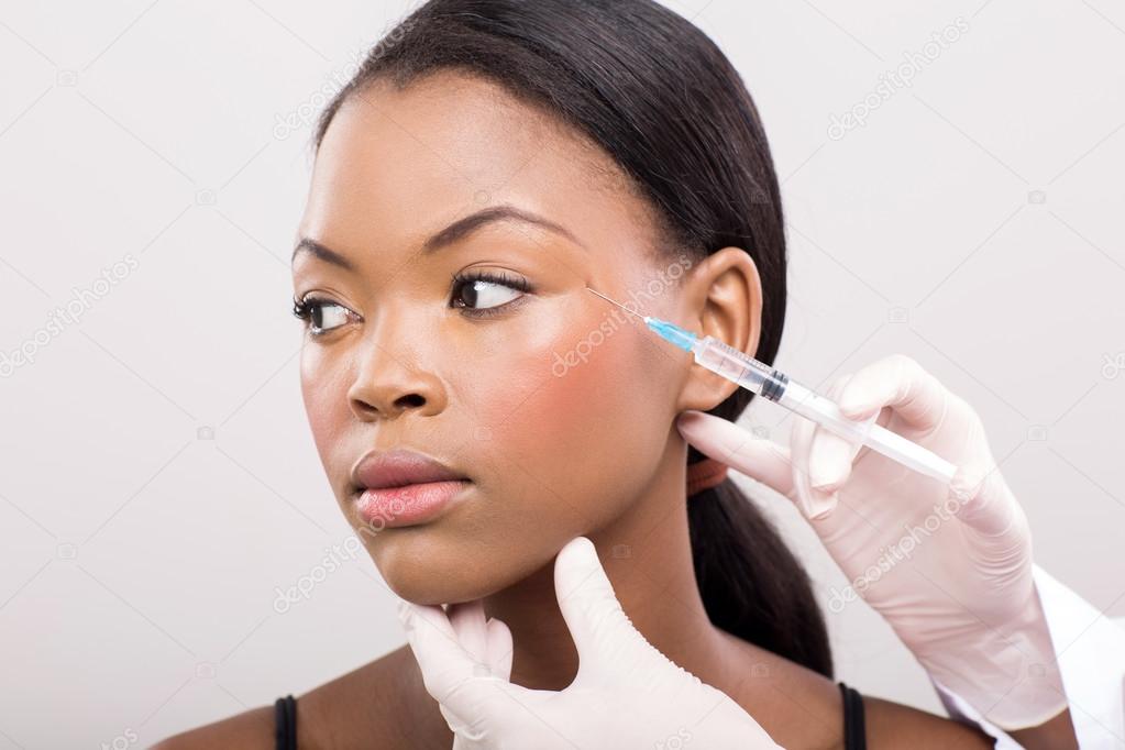 Cosmetic doctor injecting woman face