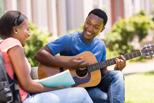 Collegestudent spela gitarr till sin flickvän — Stockfoto