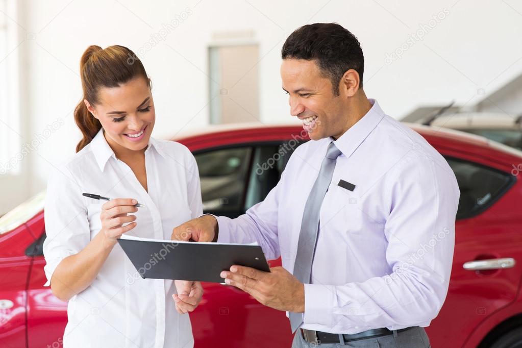 woman buying a new car at vehicle showroom