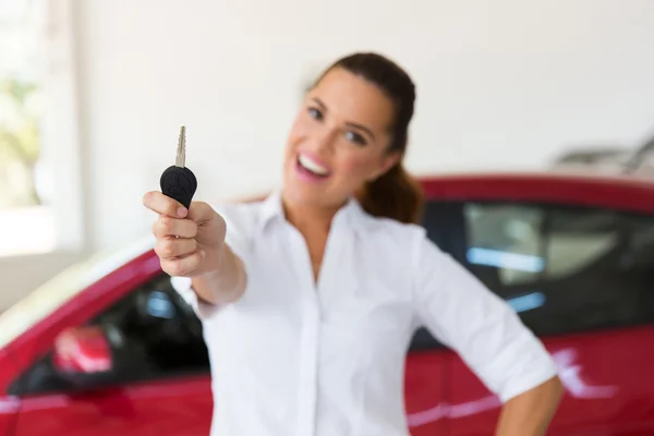 Woman showing new car key in showroom — Stock Photo, Image