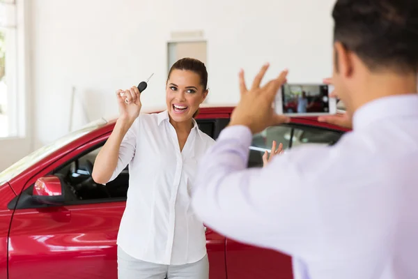 Verkäuferin fotografiert die Kundin neben ihrem neuen Auto — Stockfoto