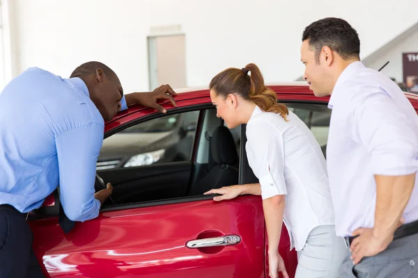 Venditore che mostra auto nuove a una coppia — Foto Stock