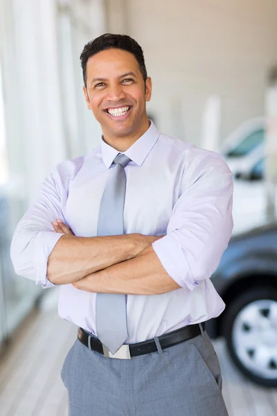 Vehicle salesman with arms crossed in car showroom — Stock Photo, Image