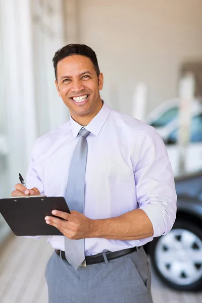 Concessionário de automóveis que trabalha no showroom — Fotografia de Stock