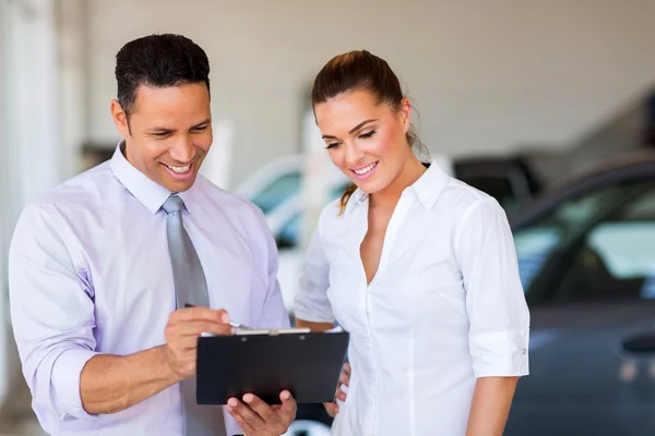 Autohaus-Chefin und Verkäuferin schauen auf Klemmbrett — Stockfoto