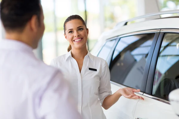 Vendeuse montrant une nouvelle voiture à un client — Photo