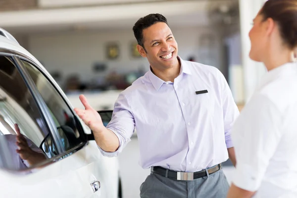 Salesman selling car to a customer in showroom — Stock Photo, Image