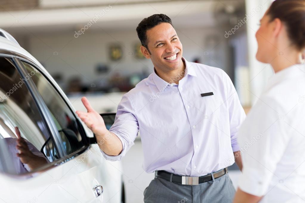 salesman selling car to a customer in showroom