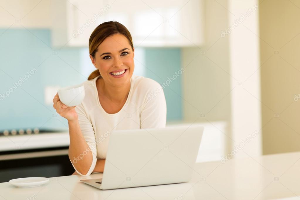 woman drinking coffee and using laptop
