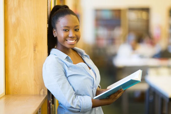 Chica universitaria sonriendo en la biblioteca — Foto de Stock