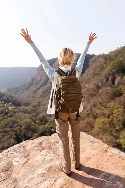 女性的徒步旅行者双臂张开在山的峭壁上 — 图库照片