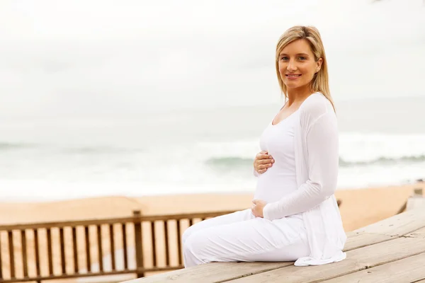 Femme enceinte assise près de la plage — Photo