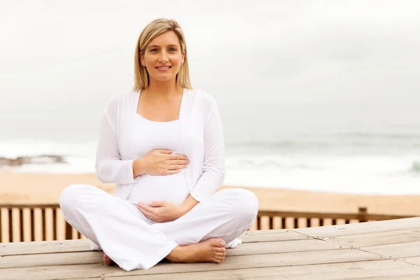 Mujer tocando la barriga en la playa — Foto de Stock