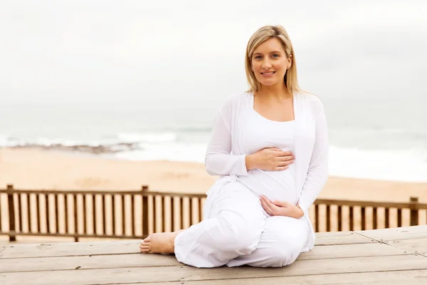 Woman touching tummy on beach — Stock Photo, Image