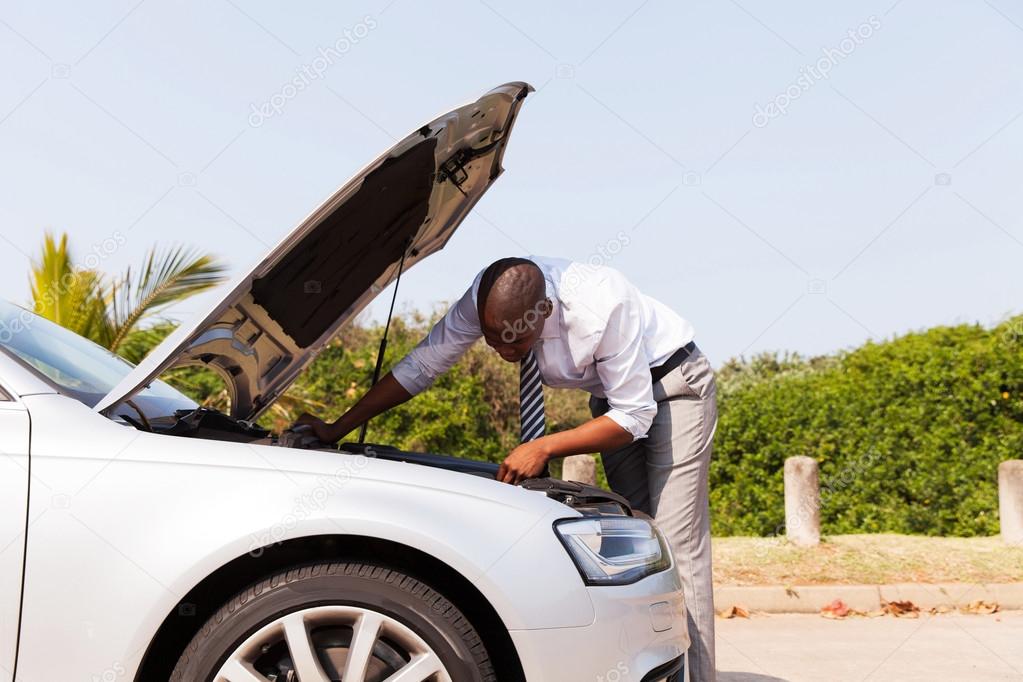 man looking at car engine