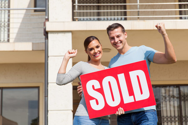 couple holding sold sign