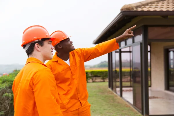 Werknemers in de bouw wijzend op huis — Stockfoto